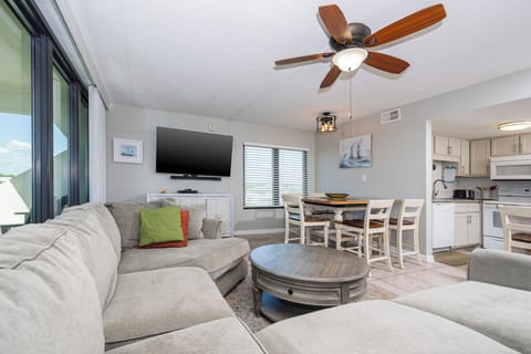 The living space features a comfortable sectional sofa, a stylish coffee table, and a view through large windows