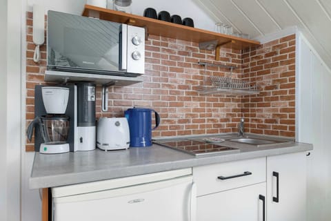 Another angle of the small kitchen, showing the stove, cabinets, and a small dining area with chairs.