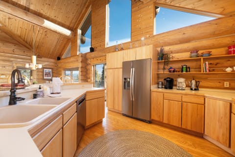 Your rustic log cabin kitchen features modern appliances and soaring ceilings that create an airy, mountain retreat atmosphere for memorable meals.