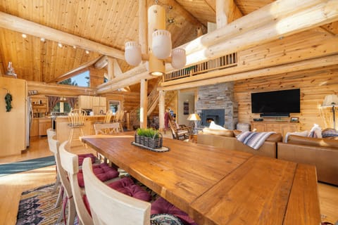 Gather around this stunning wooden dining table in your rustic log cabin retreat, where natural light floods through soaring ceilings.