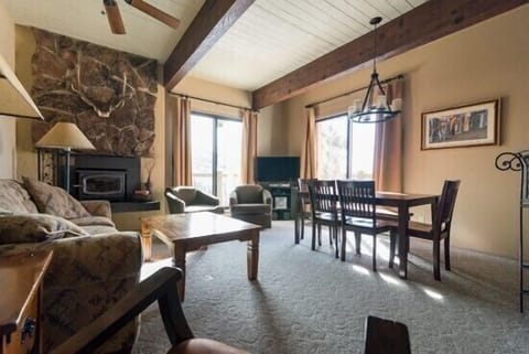 Relax in this spacious living area featuring rustic stone fireplace, exposed beams, and comfortable seating perfect for gathering after mountain adventures.