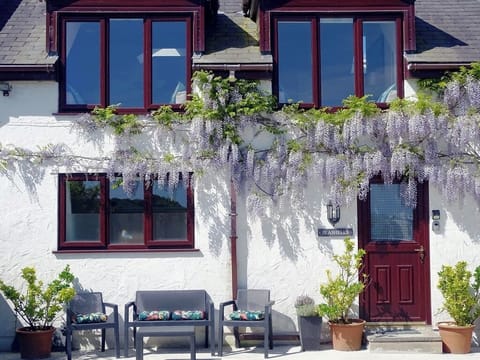 Front of Seashells with seating area, front door and the wisteria out in May