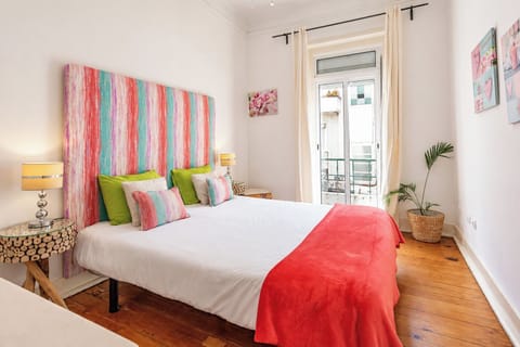 Bright double bedroom with a colorful feature headboard, bedside lighting and balcony doors.