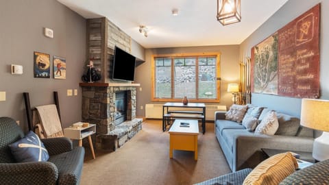 The great room features a luxury queen sofa sleeper, HDTV with streaming and cable, gas fireplace, views of the slopes, open concept kitchen, breakfast bar, dining area, and door out to the patio.