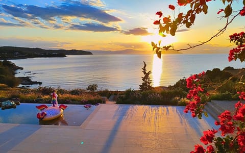 The pool and sea glow in sunset hues, offering a serene, breathtaking view.