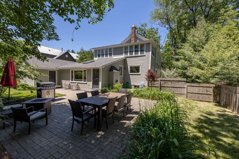 Dining table, gas firepit, gas grill, grassy play area within fenced-in yard