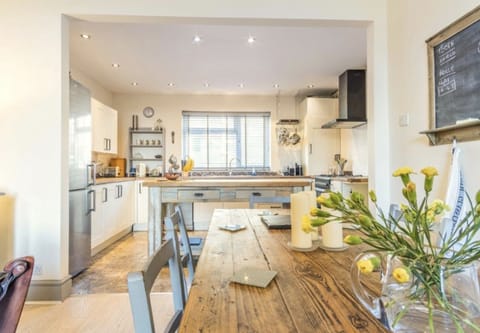 Dining table sitting room with kitchen and breakfast bar.