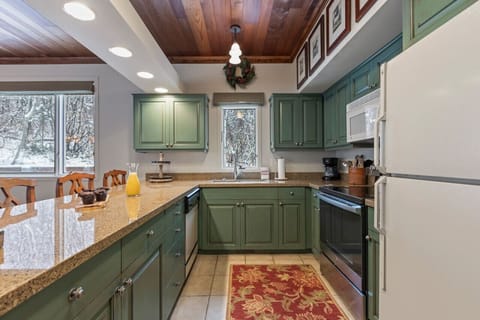 A gourmet kitchen with a large island with bar stools. Adjacent to the kitchen is an open dining area with a spacious table that seats up to 6. This space is ideal for entertaining and large gatherings, with ample natural light and mountain view
