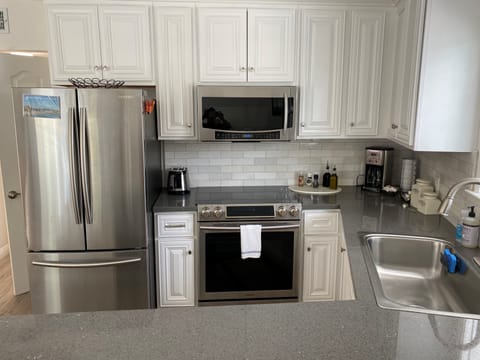 Kitchen with microwave, oven, glass top stove, fridge with ice maker, dishwasher