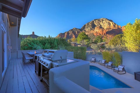 Outdoor patio with dining table and BBQ grill.