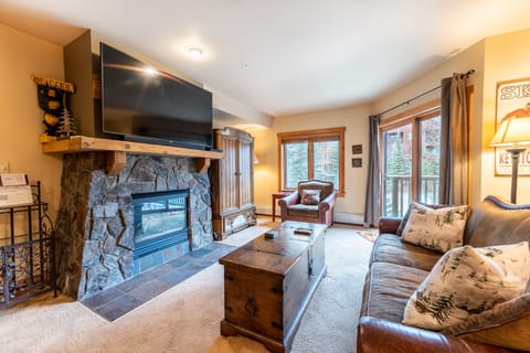 Cozy up by your stone fireplace while watching the big screen TV in this warm living room with mountain views.