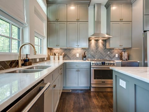 - Enjoy this bright kitchen with tall cabinetry and a sleek vent hood   - Herringbone backsplash adds style to the cooking space   - Spacious counters and natural light create a perfect kitchen setup