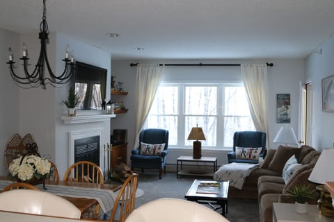 Large comfy living room with big flatscreen TV over wood burning fireplace