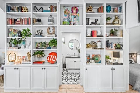 Modern apartment centered by soaring bookshelves full of art, plants, and books.