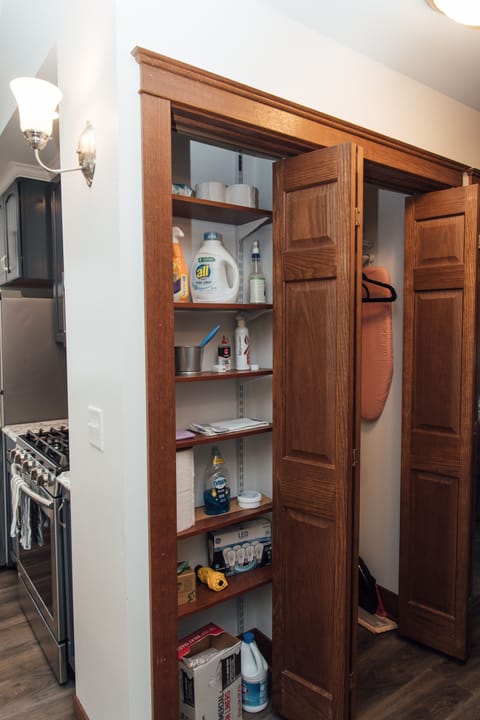 Hall closet for hanging coats (background) and pantry with household supplies.
