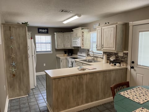 full kitchen with lots of custom chalk painted cabinets and large counter top