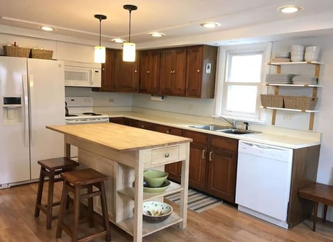 Open concept kitchen. Fully equipped kitchen includes dishwasher, microwave, refrigerator, oven,  island and two stools.
