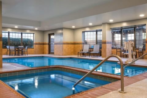 Hot tub and pool deck bathed in natural light, with cushioned lounge chairs lined along the windows