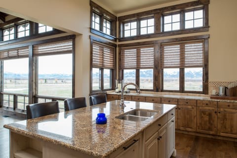 Wake up to breathtaking mountain views from this stunning rustic kitchen, where you'll love preparing meals while gazing at the expansive landscape through floor-to-ceiling windows.