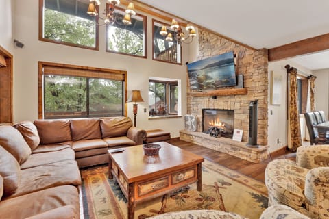 Cozy mountain living room with a stone fireplace, comfy seating, and smart TV—perfect for relaxing evenings, movie nights, and warm cabin vibes after outdoor adventures.