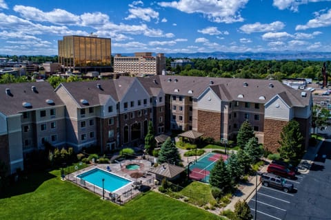 Aerial view of the outdoor pool, hot tub, and sports court with the Rocky Mountains in the background