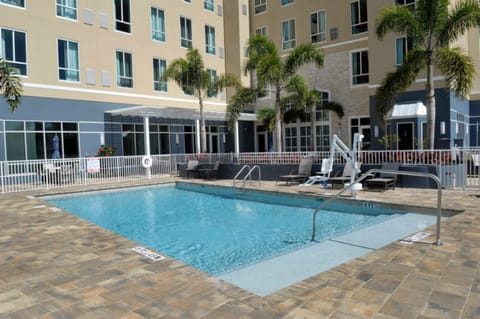 Outdoor pool surrounded by lounge chairs and palm trees.