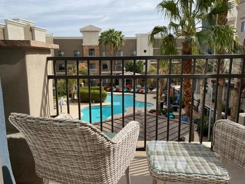Private balcony with two wicker chairs overlooking the pool and palm courtyard