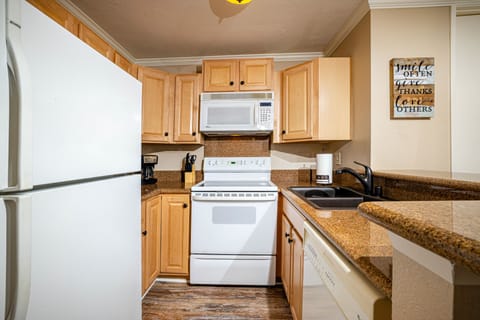 The kitchen features granite countertops, and is equipped with dishes, pots and pans, and cooking utensils.