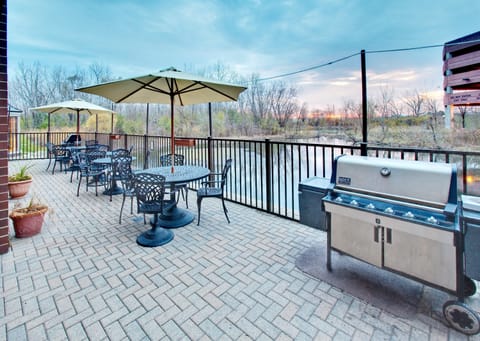 Outdoor patio seating area with tables and BBQ grill.