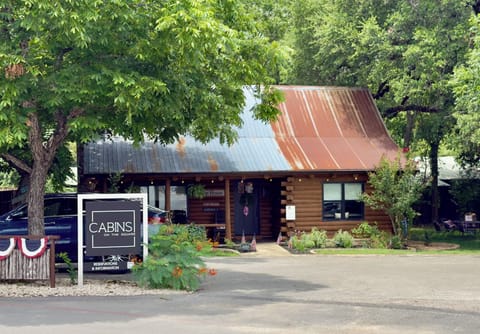 Welcome to Creek House — a log cabin front porch with rocking chairs, steps from downtown Wimberley.
