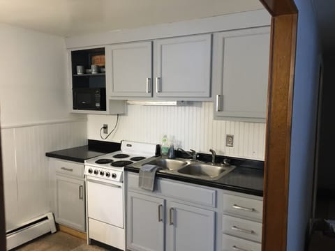 fully stocked kitchen, with a microwave, fridge, oven, coffee pot.