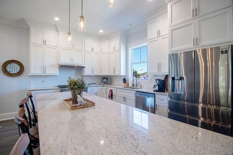 Island view towards professional gas cook top & modern 4 door refrigerator
