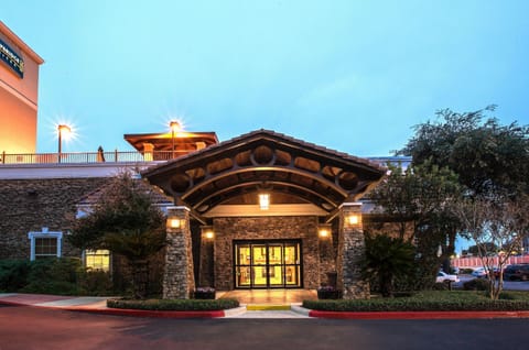 Stone-pillared entrance with tiled portico, glass double doors, and flower planters on each side