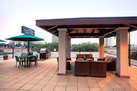 Outdoor patio with green metal dining chairs, wicker lounge seating, and a gas grill