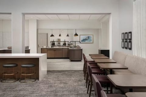 Dining area with maroon-upholstered chairs, tan booth seating, and a service counter at the rear