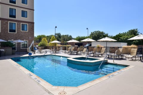 Outdoor pool with hot tub and adjacent seating area.