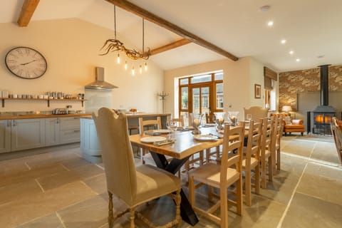 Red Stag Lodge, Little Massingham: Kitchen/ dining/ sitting area with hand-made dining table, antler chandelier, large leather sofas and wood burning stove