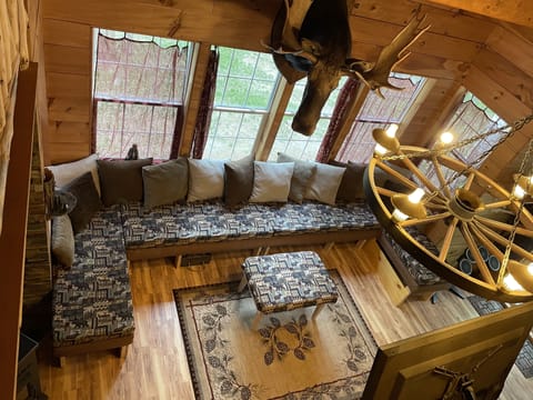 Looking down from open loft to livingroom large couch seats many.