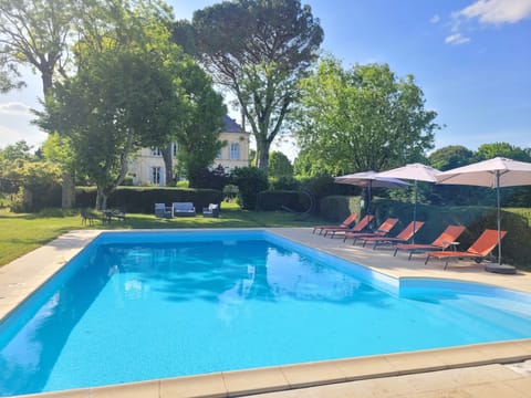 The 12 x 6 metre heated pool with sun loungers and parasols; view to the house.