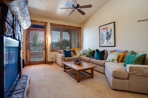 Sink into your spacious sectional with vibrant pillows, while the stone fireplace creates a cozy ambiance for your mountain retreat.