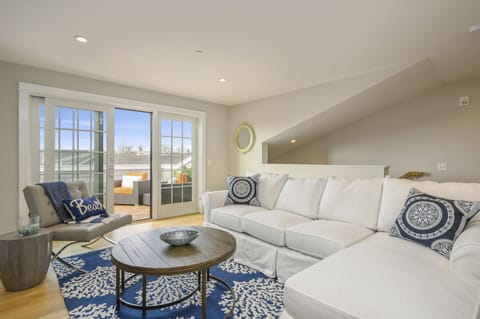 Second floor bonus room with large sectional, leather chair and entrance to roof top terrace.