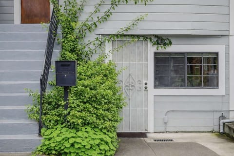 Private exterior entry with secure door, mailbox, and ivy-covered facade, offering convenient ground-level access beneath an exterior staircase.
