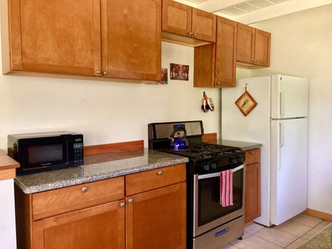 Kitchen with gas stove, microwave, coffee maker, toaster, tea kettle, pots &pans