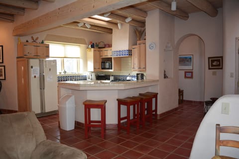 View to open kitchen with bar stools for added dining and view to arched hall to master bedroom