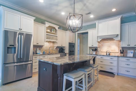 The kitchen features a central island, custom cabinetry, designer light fixtures and stone flooring.