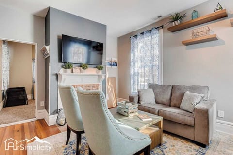 - Stylish living room with mounted TV, white fireplace mantel, and cozy neutral sofa for relaxation
- Blue accent chairs and layered rugs add charm and comfort to this welcoming space
- Sunlight filters through patterned curtains and floating shelves