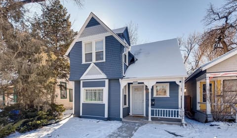 Charming two story blue home with crisp white trim, a snow covered yard, and a welcoming covered entry.

