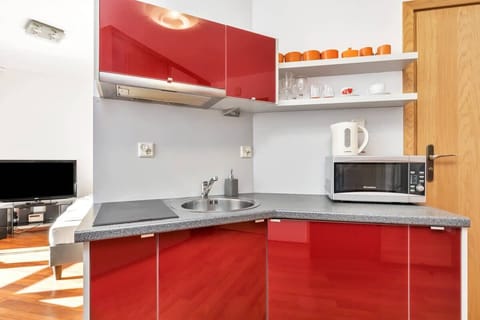 Bright red accents in the kitchenette add a playful touch to the space.
