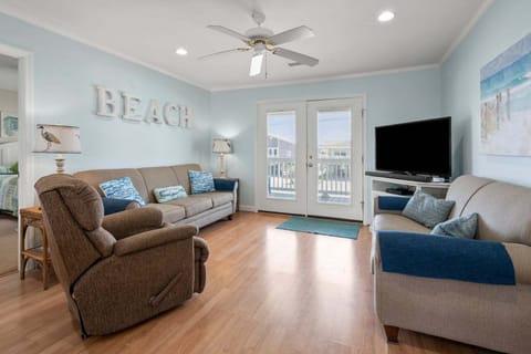 Living area with sectional seating and doors to the porch at Anchor in the Waves, a 4-bedroom Cherry Grove vacation rental