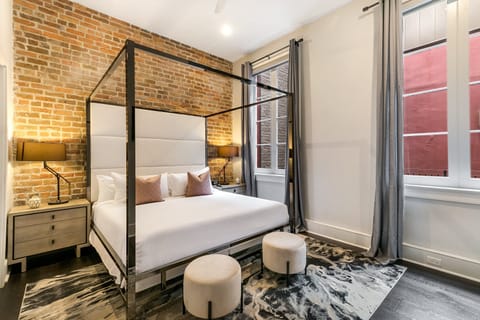 Spacious master bedroom with a king-size bed, ensuite bathroom, and designer built-in closets. Features nightstands, lamps, hangers, luggage rack. white noise machine, and a 43" Samsung Smart 4K TV with streaming and DIRECTV Entertainment.